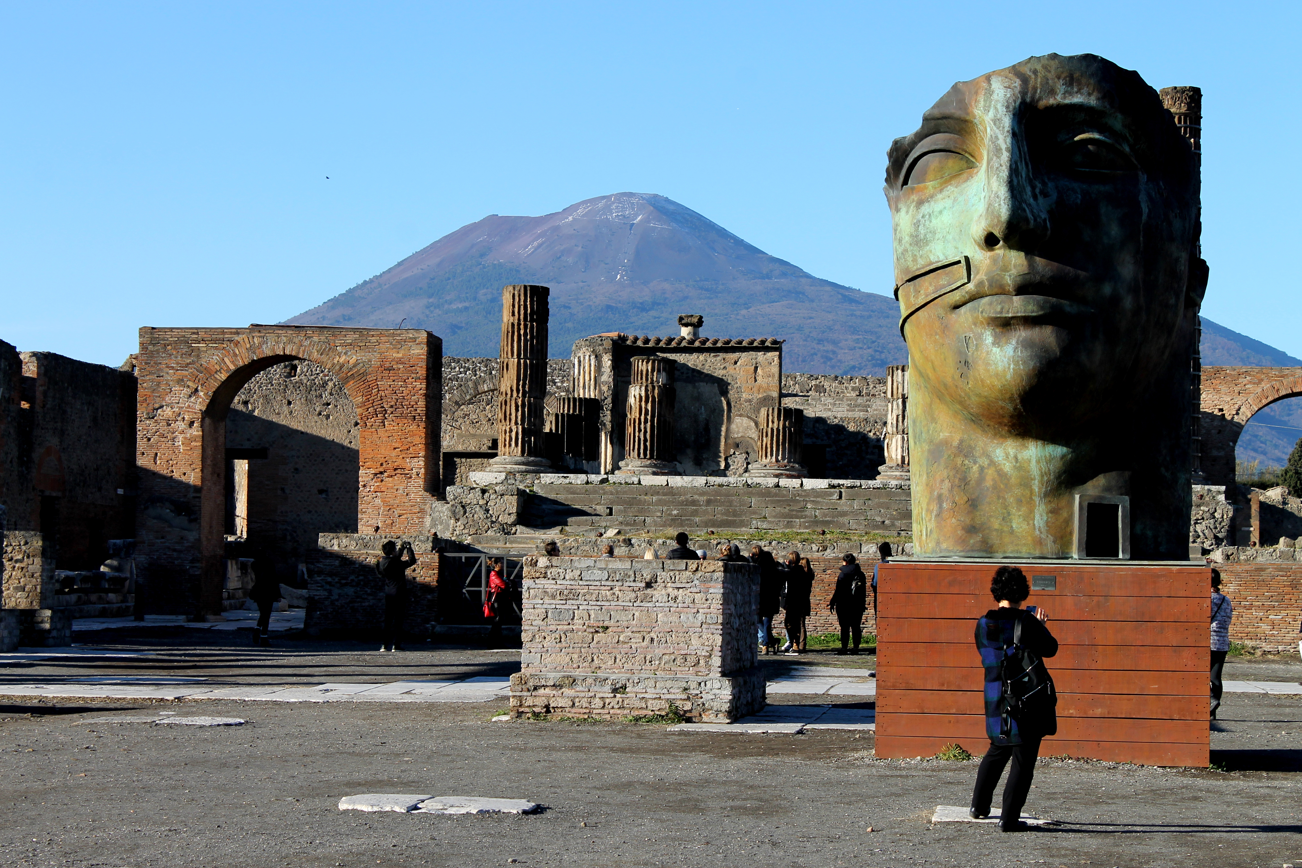 A sculpture amid the ruins of the ancient city of Pompeii, City of Naples, Campania, Italy, with Mt Vesuvius in the background.